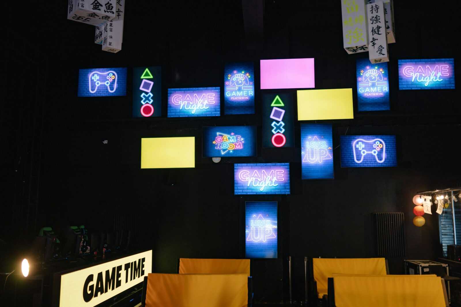 A lively gaming room displaying bright neon signs and screens, creating an immersive atmosphere.